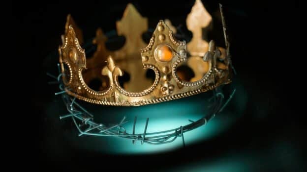 Gold crown resting on twisted barbed wire, set against a dark background, symbolizing power and oppression.