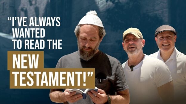 Three men outdoors; the man in front reads a book while bold text proclaims, "I've always wanted to read the New Testament!"
